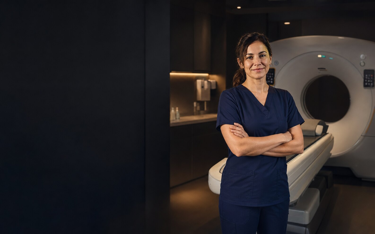 CT technologist standing beside a CT scanner